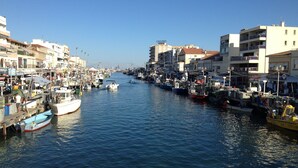 Un puerto deportivo con barcos amarrados a lo largo de un canal estrecho, rodeado de edificios con balcones y diversos letreros.