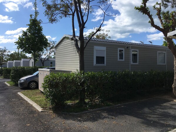 Una casa mobile a un piano con garage, un'auto parcheggiata davanti e un prato curato.