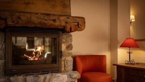 A stone fireplace with a glass door, a red chair, and a red table lamp. - 300m from ski lifts, fitness, sauna, hammam, balcony, fireplace or stove, ski locker, 120m² (Valloire)