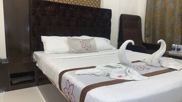 A hotel room with a large bed, a dark headboard, and a woven wall decoration.