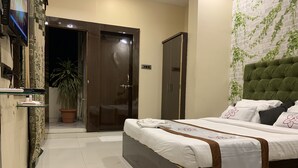 A hotel room with a bed, a wardrobe, a potted plant, and a television on the wall. - JK Rooms 126 Parashar Legacy - Station (Nagpur)