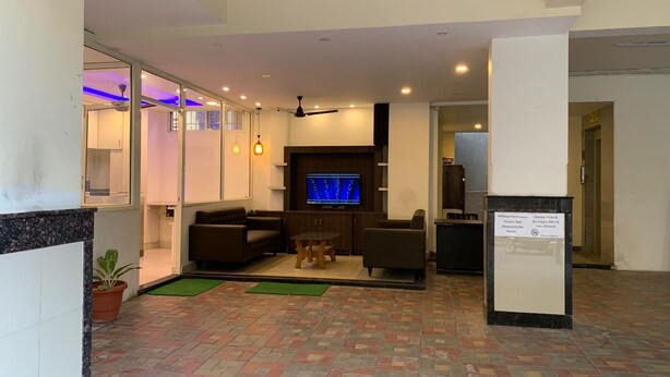 A lobby with a seating area, a television, and a sign indicating no outside food or beverages. - JK Rooms 126 Parashar Legacy - Station (Nagpur)