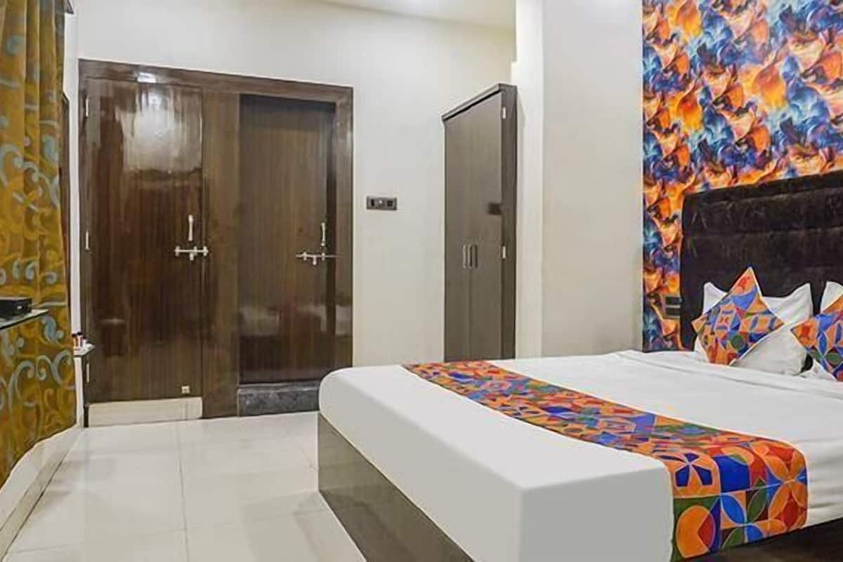 Een slaapkamer met een bed, een televisie, een kledingkast en een kleurrijke muur.