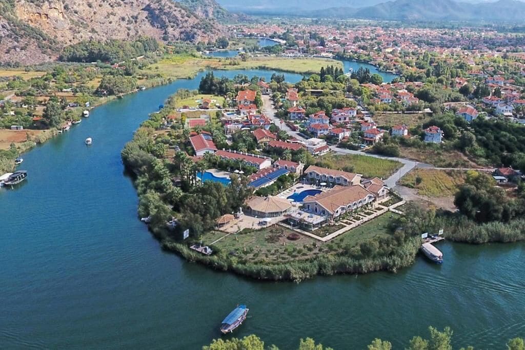 A riverside residential area with houses, a swimming pool, and boats.