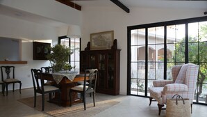 A dining area with a wooden table, chairs, and a cabinet. There is a large window with a view of the outdoors. - Dalyan Holiday Hotel (Ortaca)