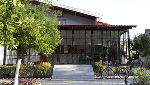 A modern building with large glass windows, a covered entrance, and a bicycle parked outside. - Dalyan Holiday Hotel (Ortaca)