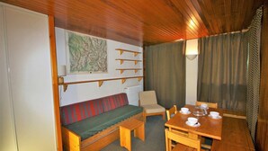 Una habitación acogedora con un banco de madera, una mesa de comedor con sillas y un radiador.