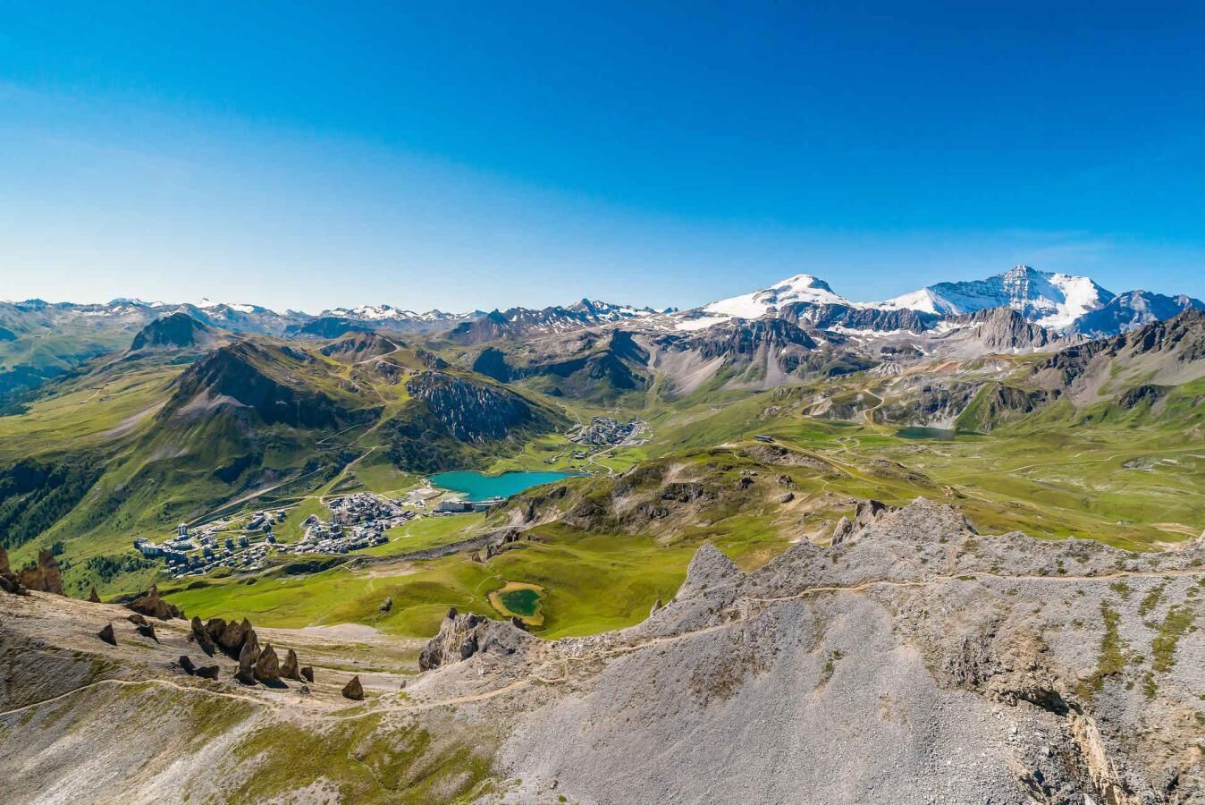 Paesaggio montuoso con un piccolo insediamento e un lago.