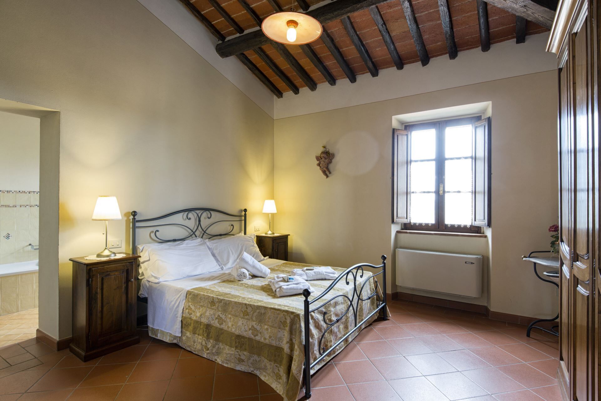 Um quarto com uma cama, duas mesas de cabeceira, uma janela e um radiador.