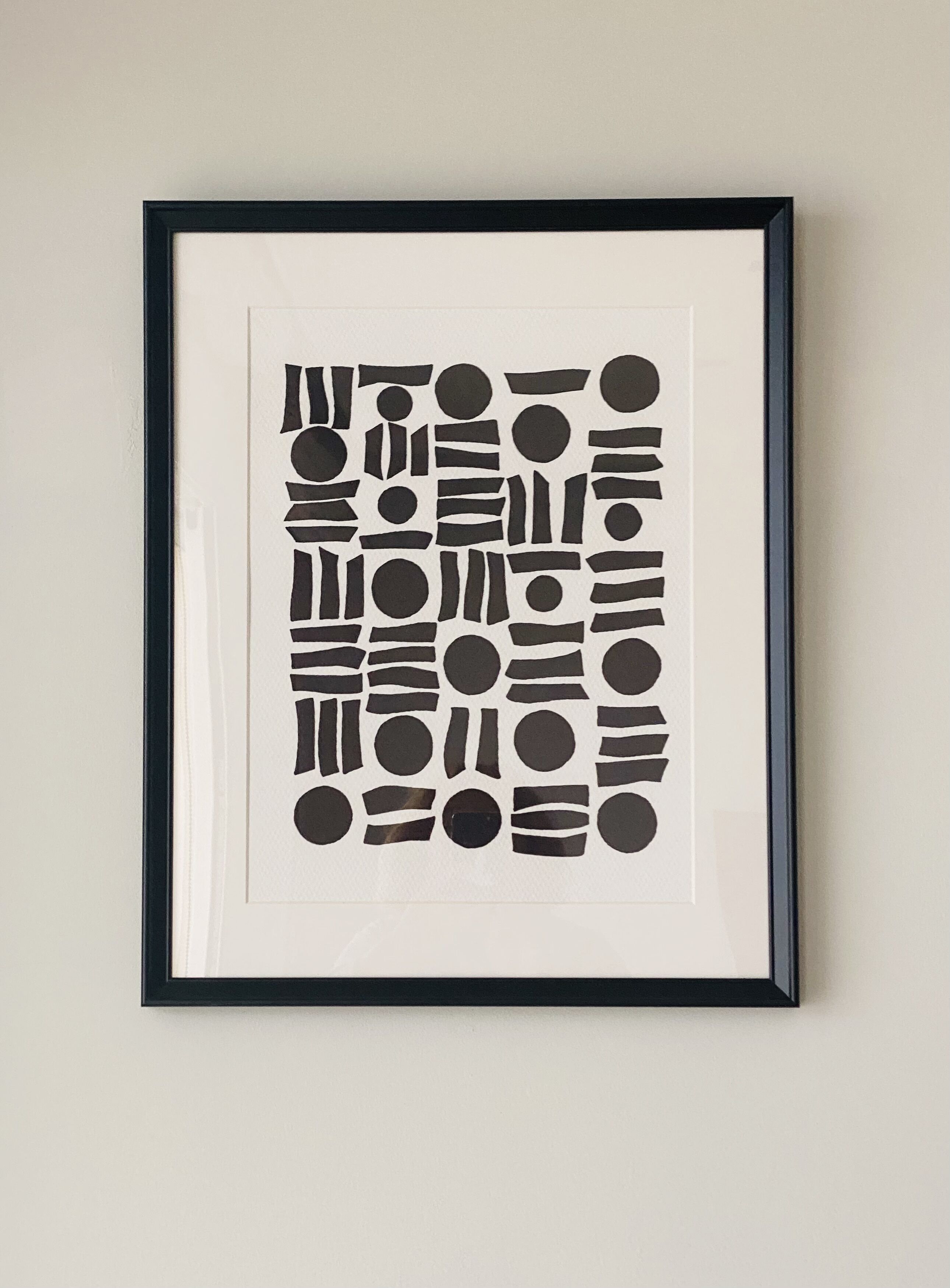 A framed abstract art piece with geometric shapes and lines.