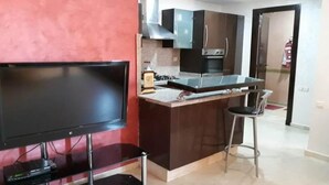A modern kitchen with a central island, a flat-screen TV, and a bar stool. - Charming little studio in Marrakech 4095 (Marrakech)