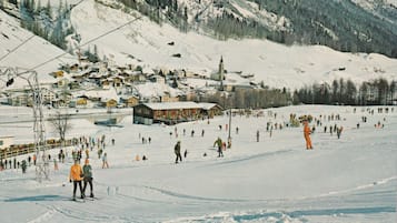 A ski resort with multiple buildings, a ski lift, and a snowy landscape.