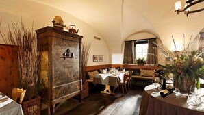 A cozy dining area with a wooden cabinet, a table set for two, and a bench. - Hotel Bodenhaus (Rheinwald)