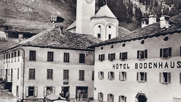 A historic hotel with a prominent clock tower, surrounded by mountainous terrain.