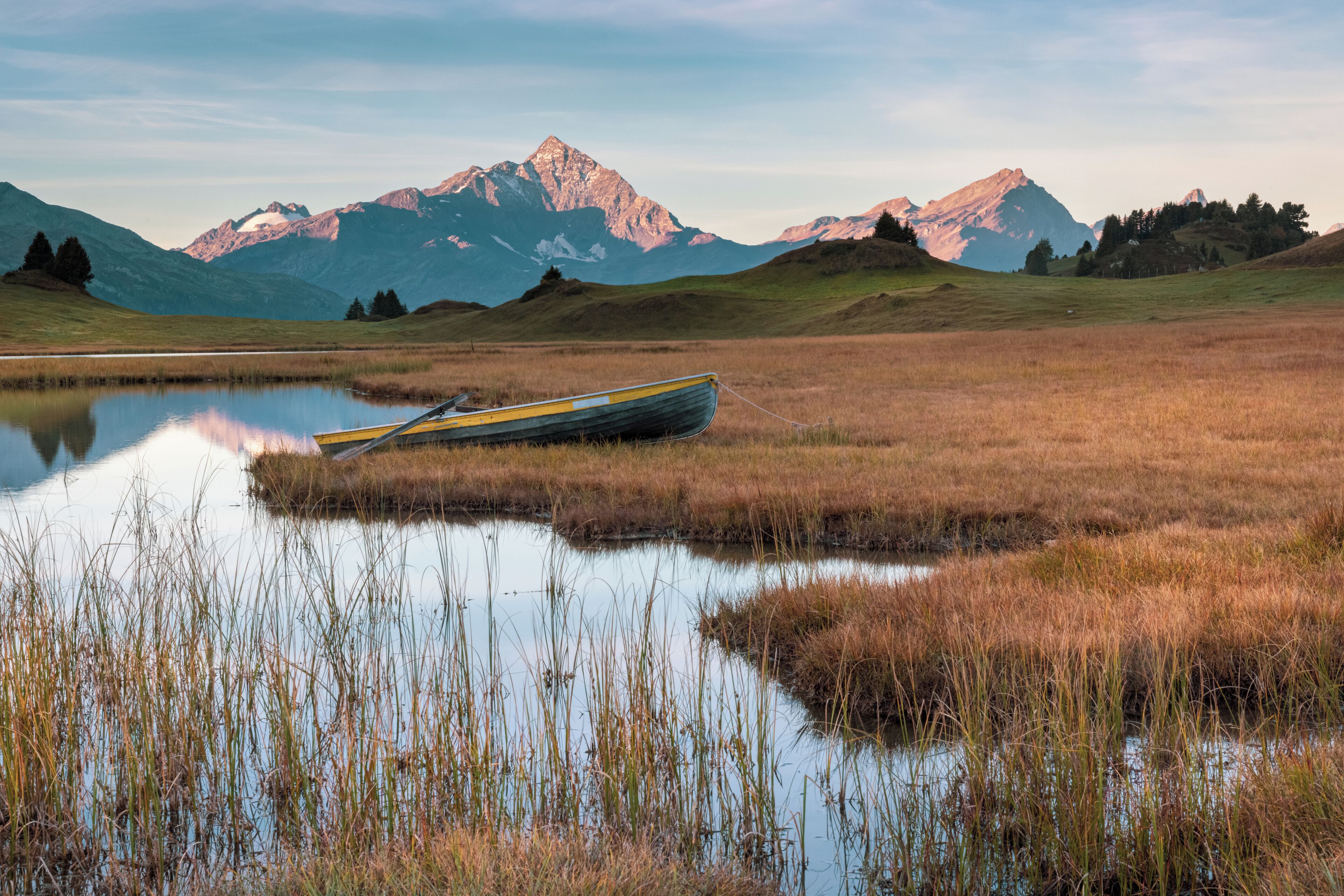 A boat in a calm lake with mountains in the background.