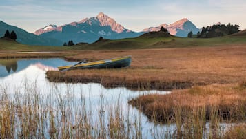 A boat in a calm lake with mountains in the background.