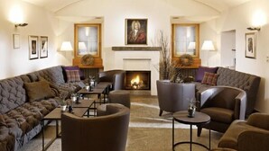 A cozy living room with a fireplace, leather sofas, and a coffee table. - Hotel Bodenhaus (Rheinwald)