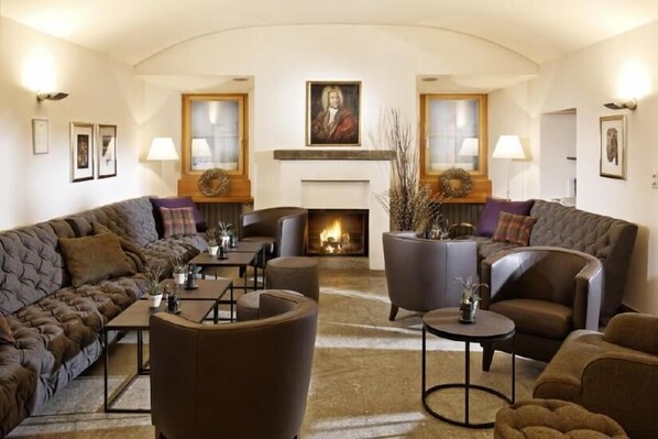A cozy living room with a fireplace, leather sofas, and a coffee table. - Hotel Bodenhaus (Rheinwald)
