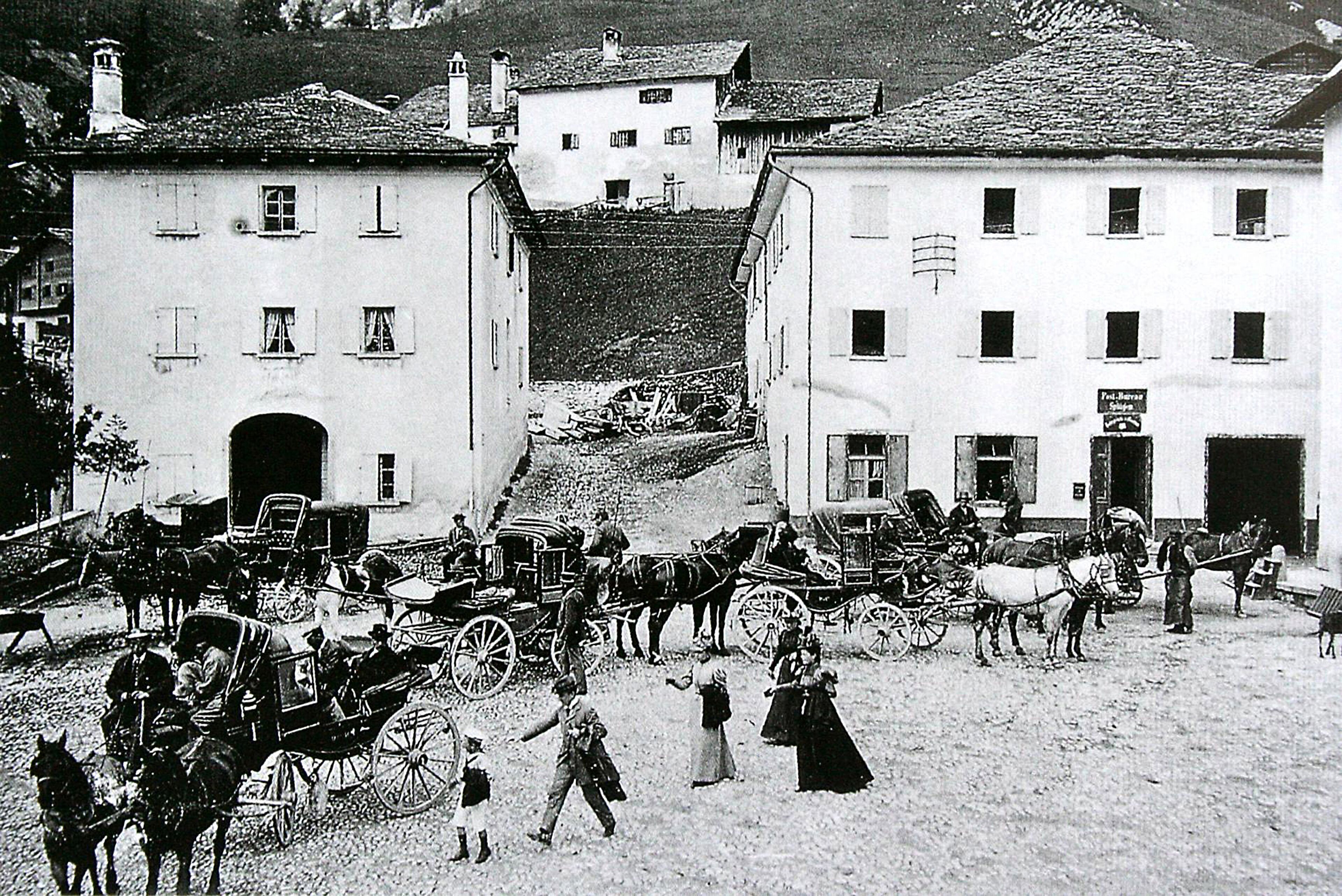 A historical street scene with horse-drawn carriages and pedestrians.