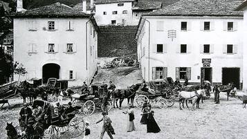 A historical street scene with horse-drawn carriages and pedestrians.