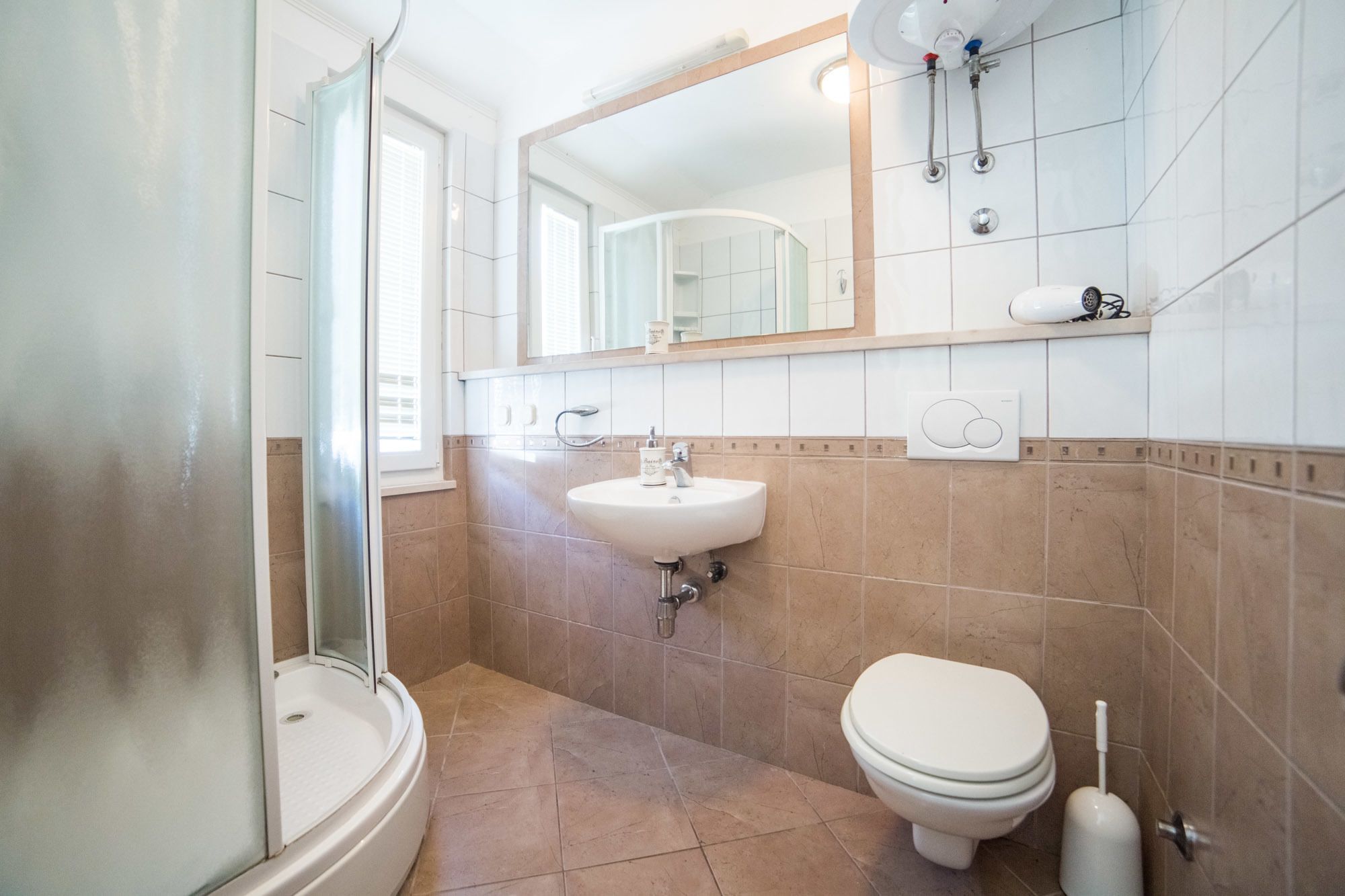 Un bagno con doccia, lavandino, water e specchio.