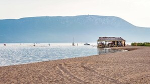 A beach with a small hut and a boat in the water.