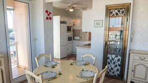 A dining area with a round table, four chairs, and a glass set. - Port des Sables by Interhome (Saint Cyprien)