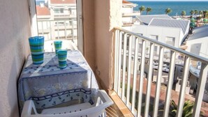 A balcony with a table, three striped cups, and a white chair. - Port des Sables by Interhome (Saint Cyprien)