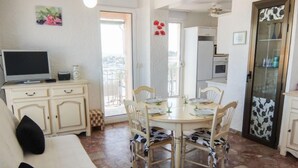 A dining area with a round table, chairs, and a television on a cabinet. - Port des Sables by Interhome (Saint Cyprien)