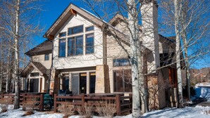 A two-story lodge with a stone facade, large windows, and a wooden deck.