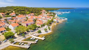 Ein Küstendorf mit roten Dächern, einem Yachthafen und klarem, türkisblauem Wasser.
