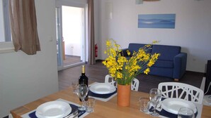 Ein Essbereich mit einem Tisch für vier Personen, einem blauen Sofa und einer Vase mit gelben Blumen.