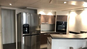 A modern kitchen with stainless steel appliances, a built-in water dispenser, and wooden cabinets. - Apartment at the foot of Cannes Port of 70m2 (Cannes)