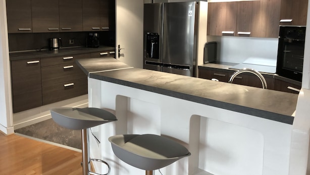 A modern kitchen with dark wood cabinets, stainless steel appliances, and a central island with stools. - Apartment at the foot of Cannes Port of 70m2 (Cannes)