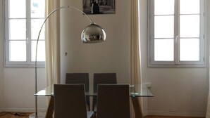 A dining area with a glass table and chairs, an air conditioning unit, and large windows with curtains. - Apartment at the foot of Cannes Port of 70m2 (Cannes)