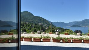 A terrace with potted plants and a view of a lake and mountains. - Agriturismo Il Colle (Bellagio)
