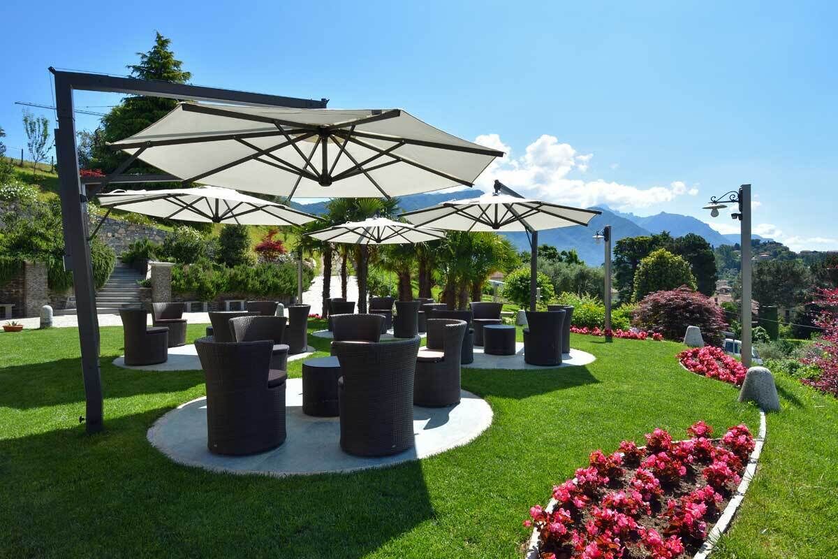 A garden with outdoor seating, umbrellas, and a view of mountains.