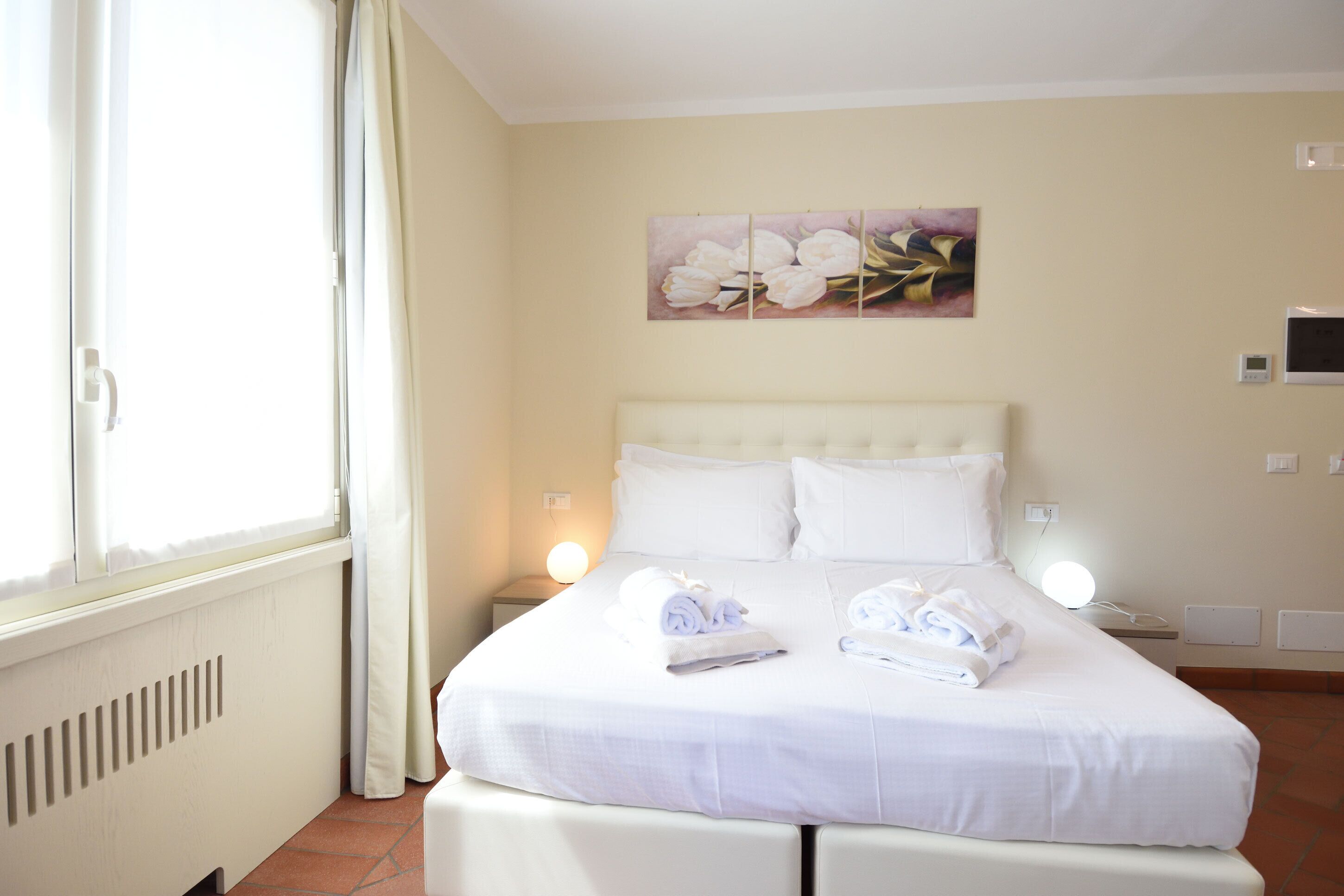 A neatly made bed with towels, a white headboard, and a wall-mounted artwork.