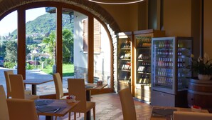 A restaurant with outdoor seating, a view of the countryside, and a refrigerator stocked with beverages. - Agriturismo Il Colle (Bellagio)