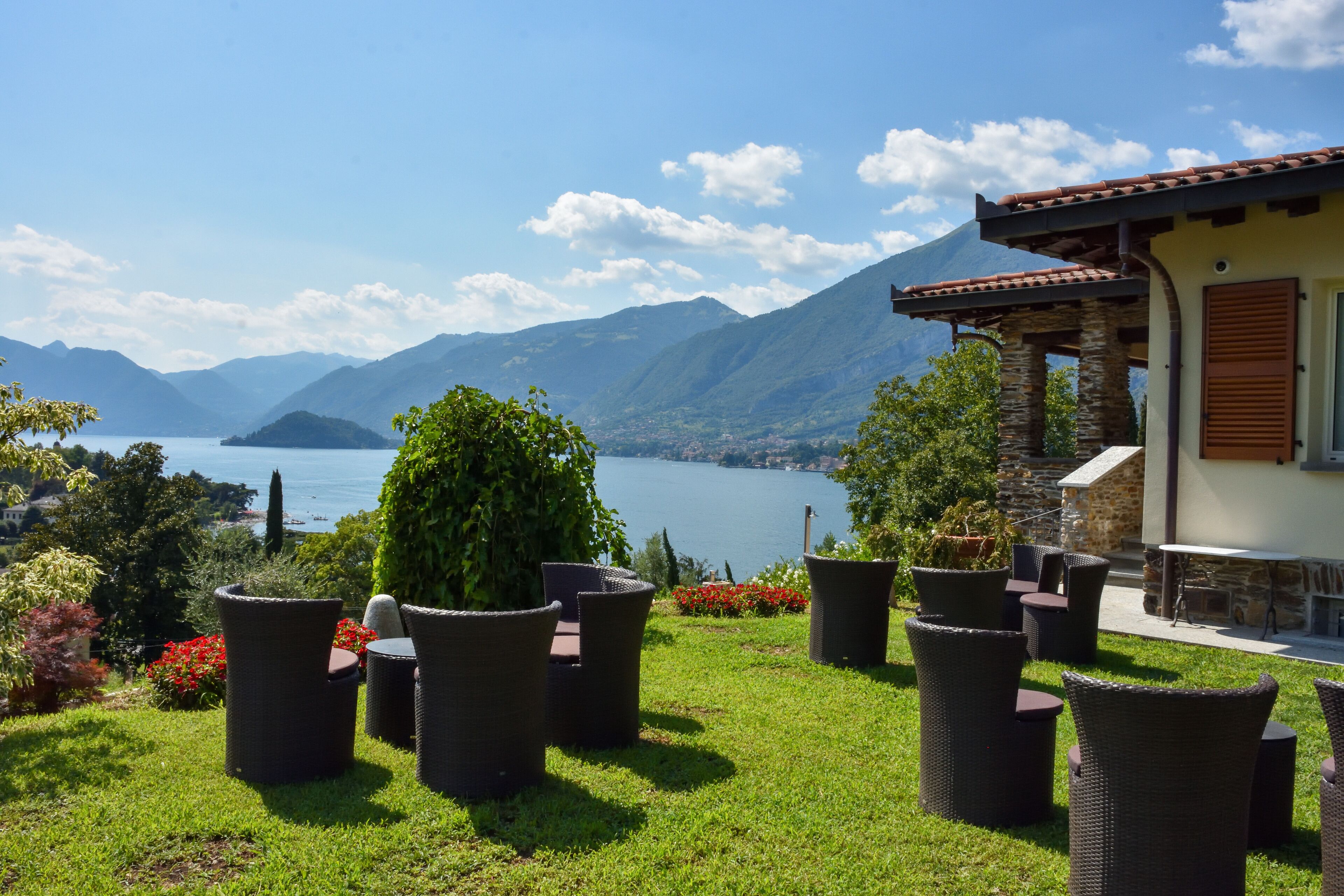 A patio with wicker furniture overlooking a lake and mountains.