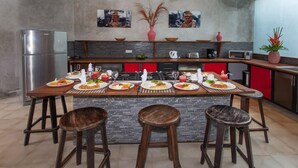 Une cuisine moderne dotée d’un îlot central, de tabourets de bar et d’un réfrigérateur en acier inoxydable.