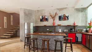 Une cuisine moderne dotée d’un îlot central, de tabourets de bar, d’un réfrigérateur et d’un meuble rouge.