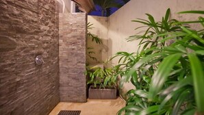 Un área de ducha pequeña y cerrada con paredes de piedra y piso de baldosas.