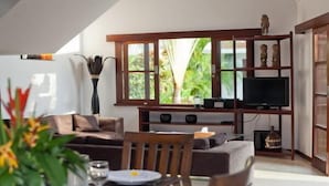 Una sala de estar moderna con un sofá, una mesa de comedor y un televisor sobre un mueble de madera.