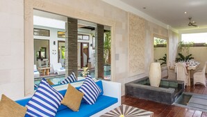 Ein stilvoller Lounge-Bereich mit einem blauen Sofagarnitur, einem Holztisch und Blick auf einen Pool.