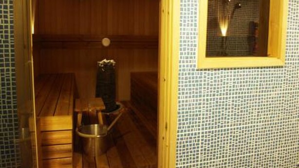 A sauna room with wooden benches and a small table with a vase. - Rantala by Interhome (Suonenjoki)