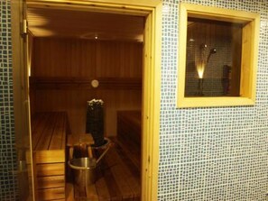 Una sala de sauna con bancos de madera y una pequeña mesa con un florero.