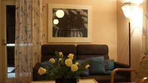 A living room with a sofa, a coffee table with a vase of flowers, a framed picture on the wall, and a floor lamp. - Rantala by Interhome (Suonenjoki)