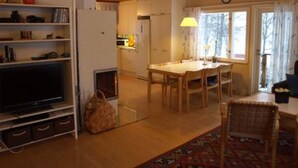 A cozy living room with a TV, wooden furniture, a dining area, and a window with curtains. - Rantala by Interhome (Suonenjoki)