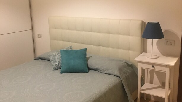 Ein Schlafzimmer mit einem Bett, einem Nachttisch, einer Lampe und drei Bildern an der Wand.